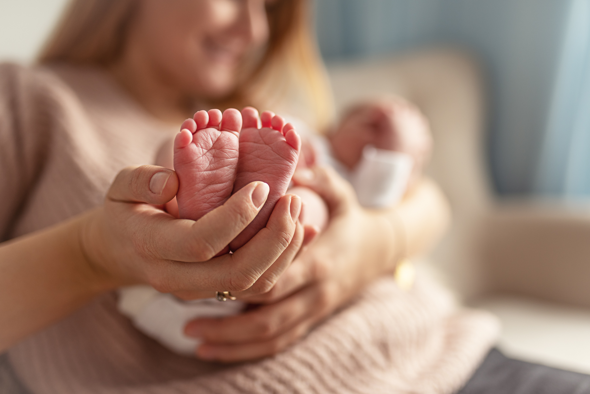 malutkie stópki noworodka w dłoniach mamy