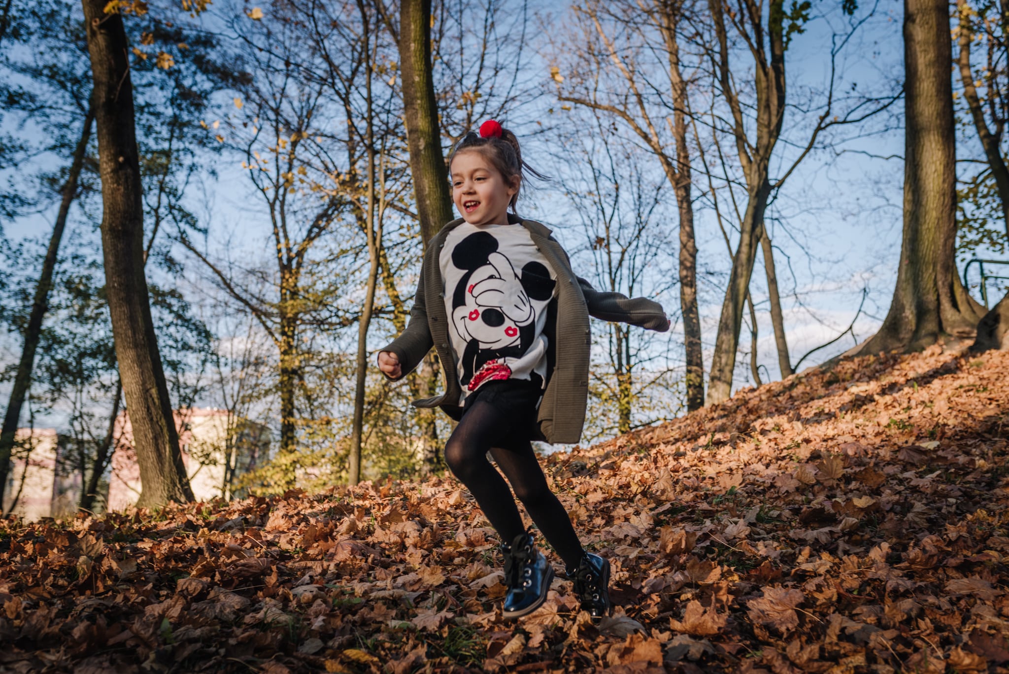 dziewczynka biegnie z górki wśród liści